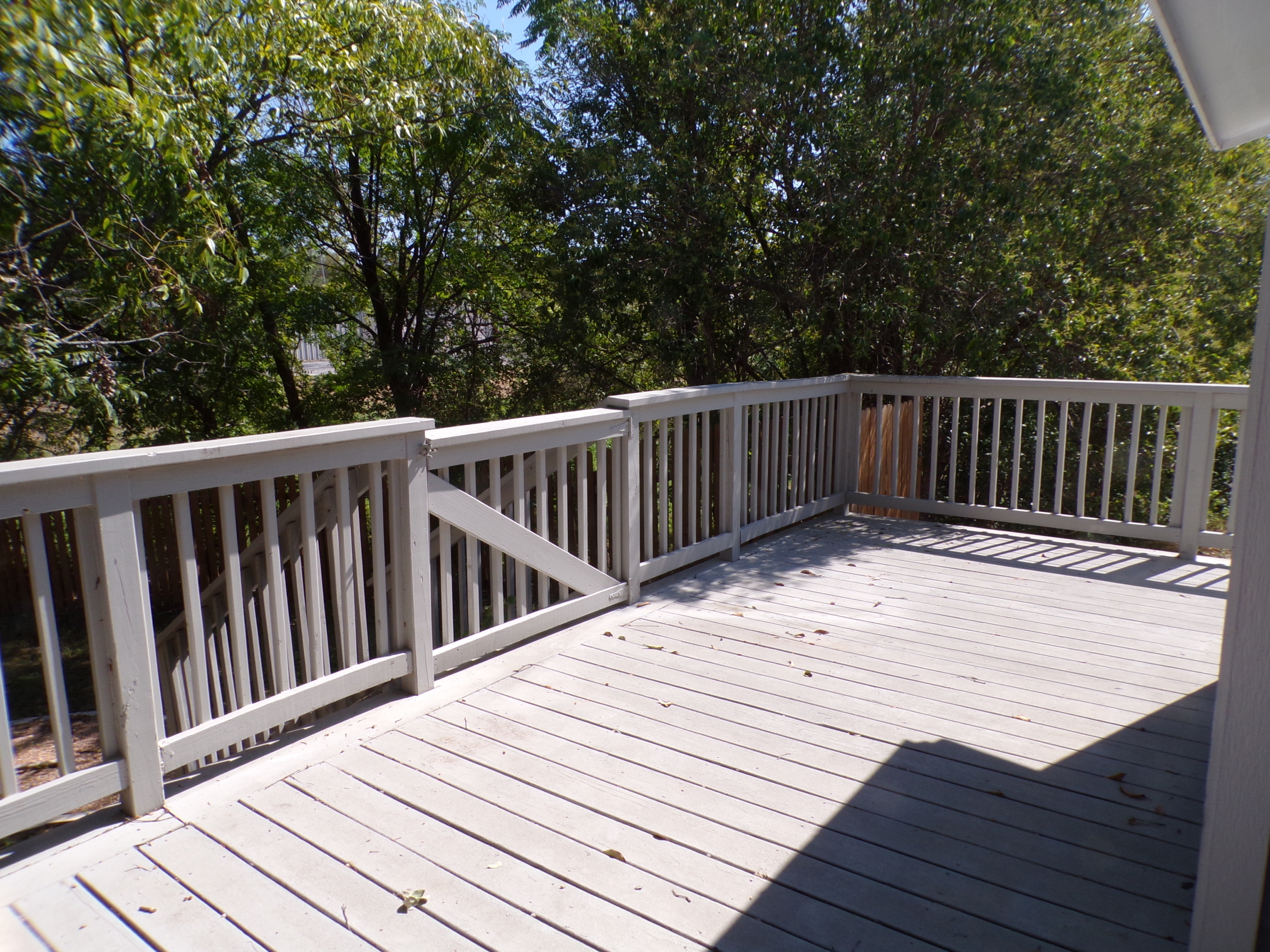 Here's an alt tag for the image: Sunny deck with white railing and stairs.
