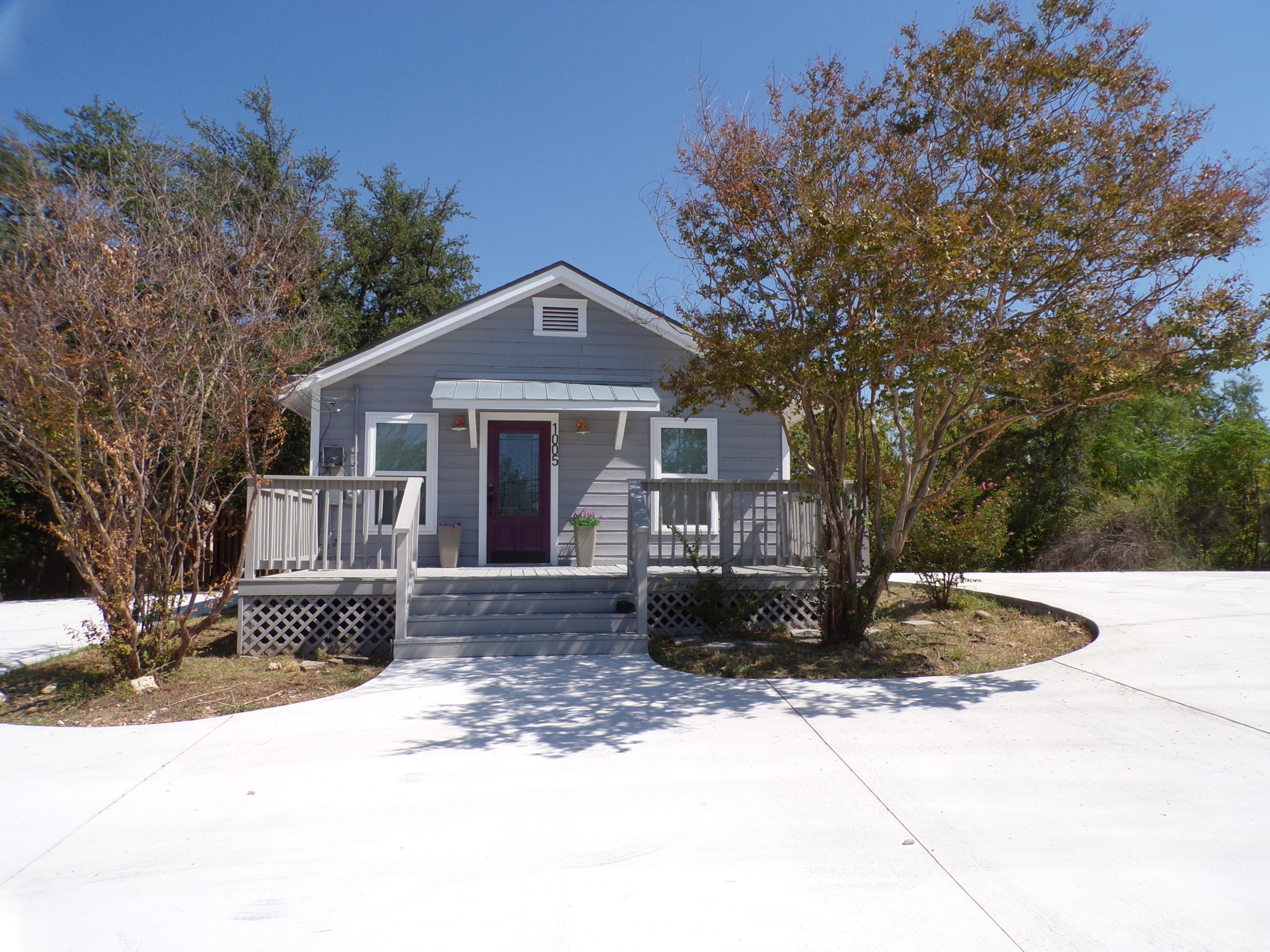 Gray house with purple door and porch.