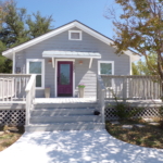 Gray house with purple door and porch.