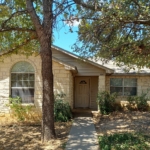 Light stone house with trees and walkway.