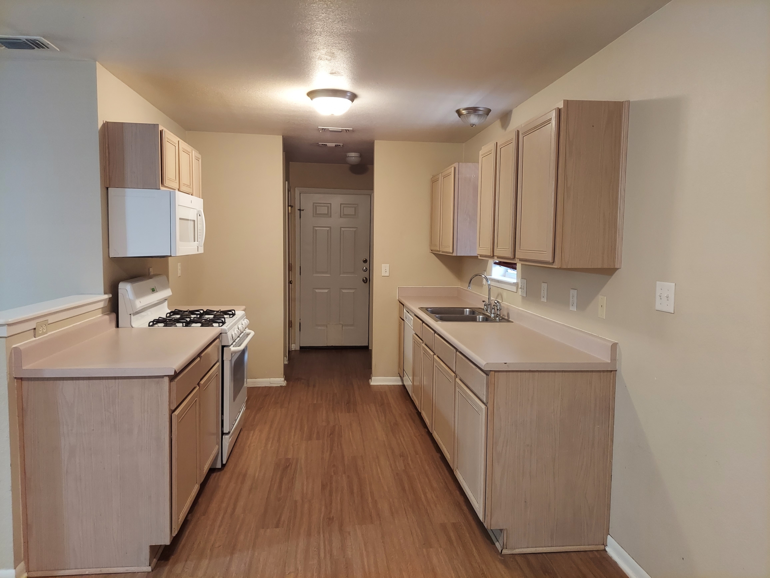 Empty light beige kitchen with wood floor.