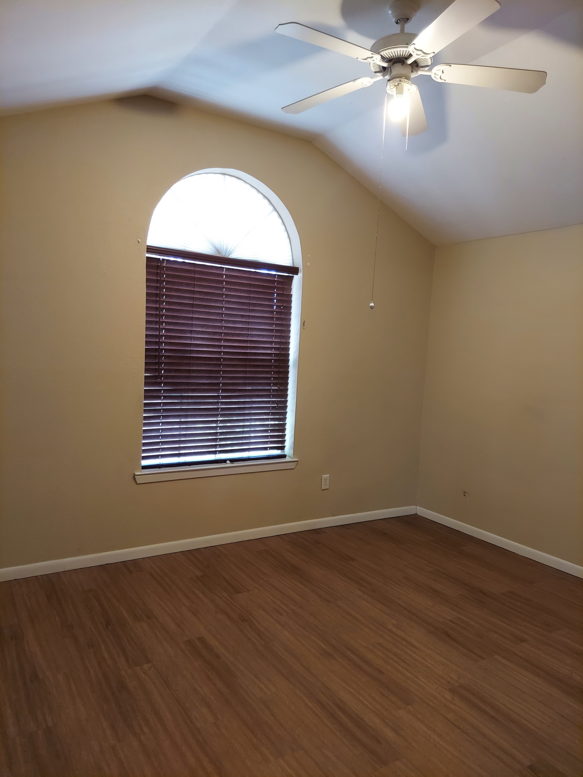 Empty bedroom with ceiling fan and window.
