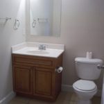 Here's an alt tag for the image: `Small bathroom with sink, toilet, and vanity`