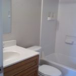 Here's an alt tag for the image: Clean, simple bathroom with tub and sink.