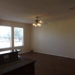 Here's an alt tag for the image: Spacious living room with large windows.
