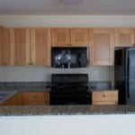 Here's an alt tag for the image: Modern kitchen with wood cabinets and black appliances.