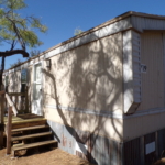 Mobile home number 19, steps, tree shade.