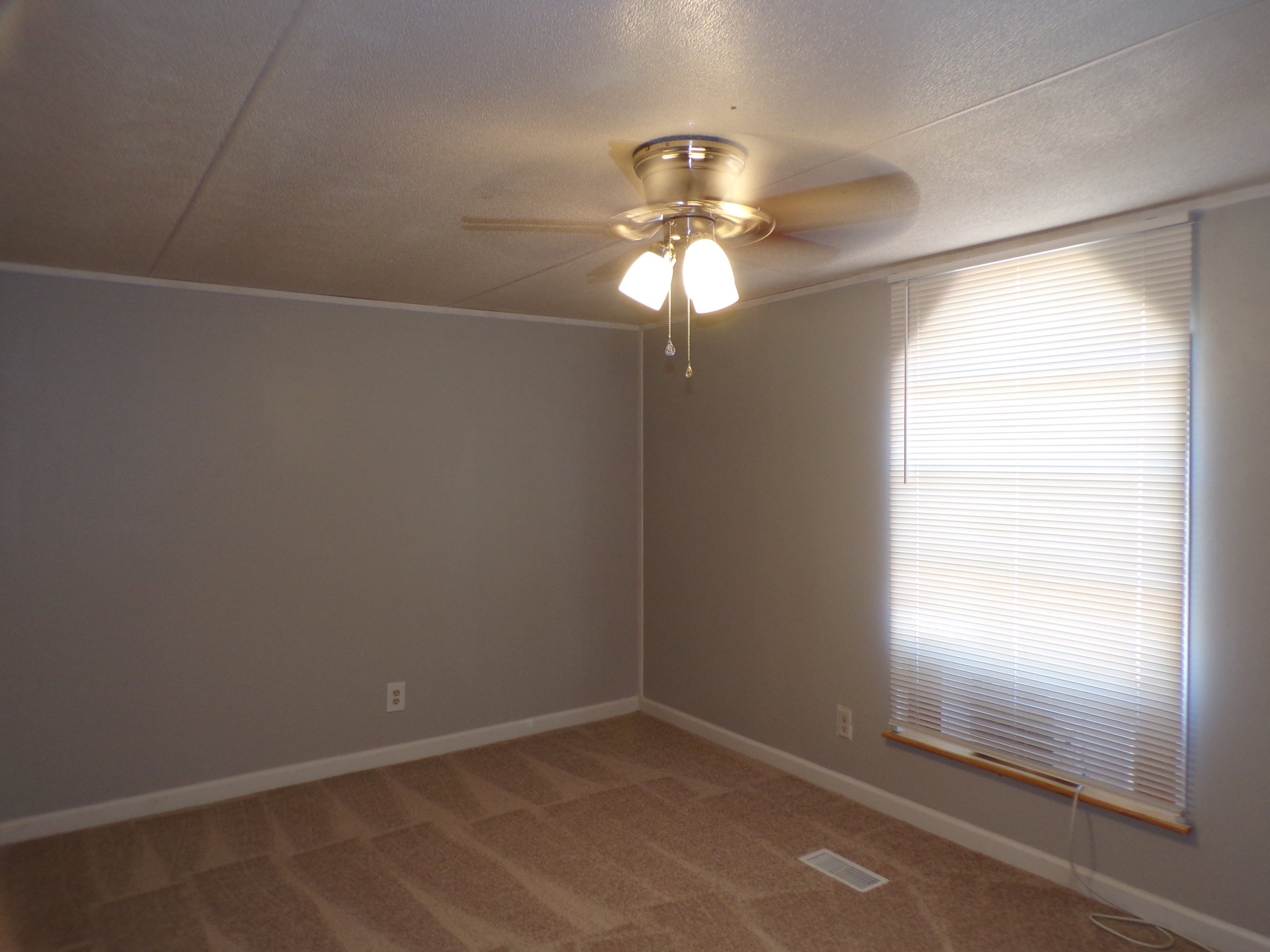 Empty bedroom with ceiling fan and blinds.