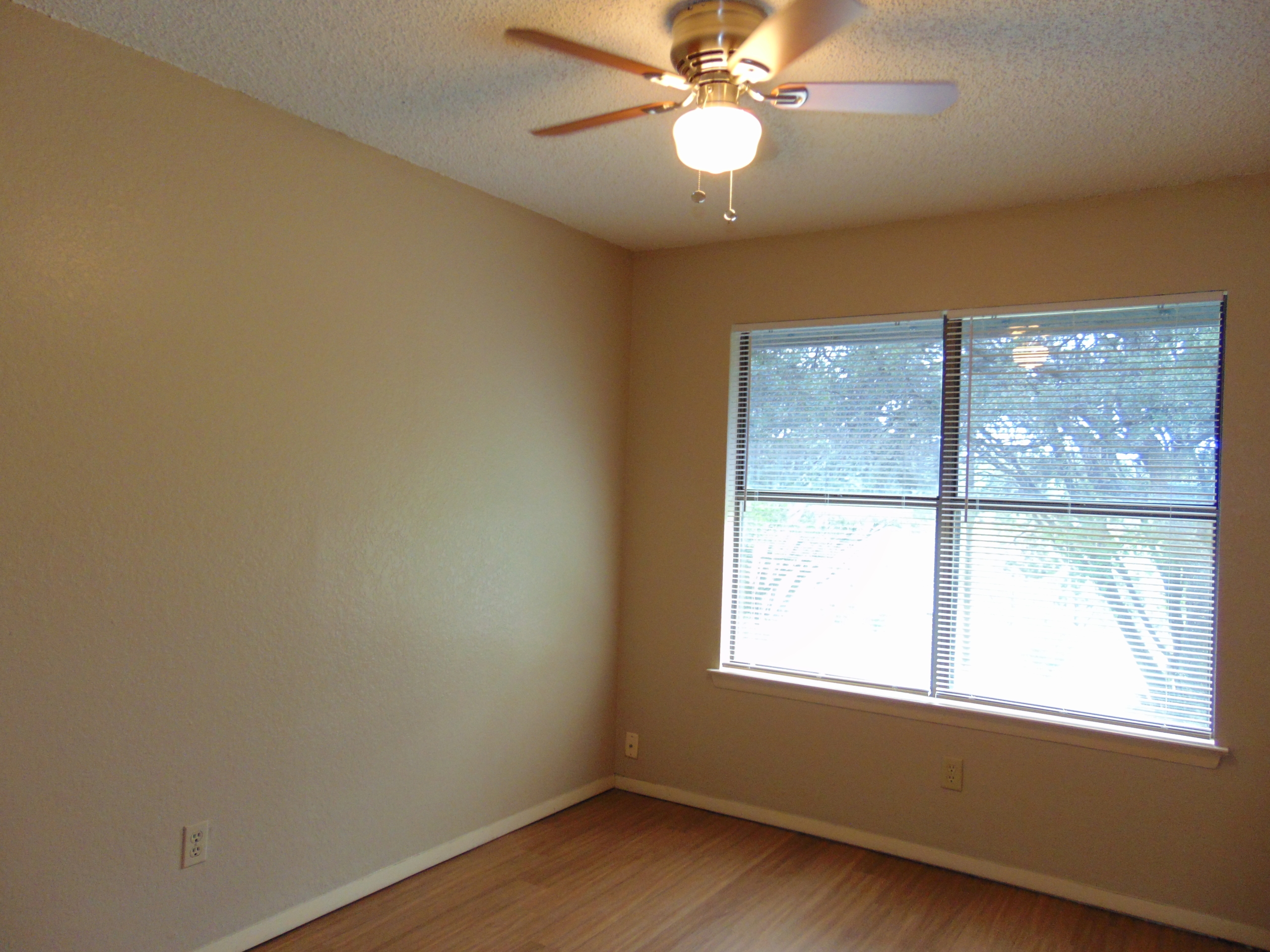 Empty beige room with ceiling fan and window.