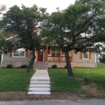 House with porch, trees, and lawn.