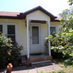 Yellow house with gray door and steps.
