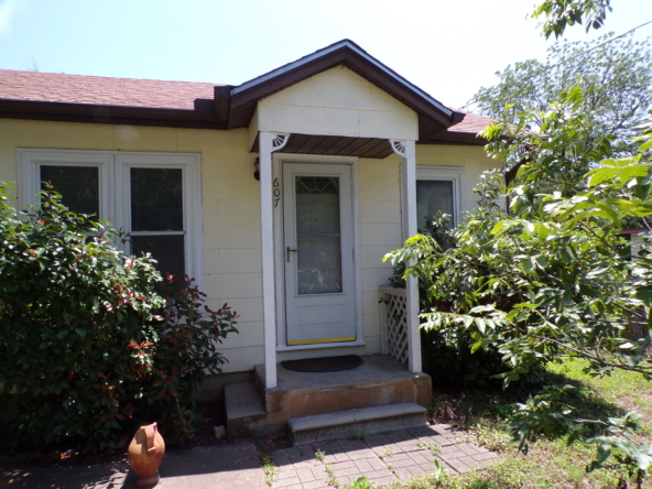 Yellow house with gray door and steps.